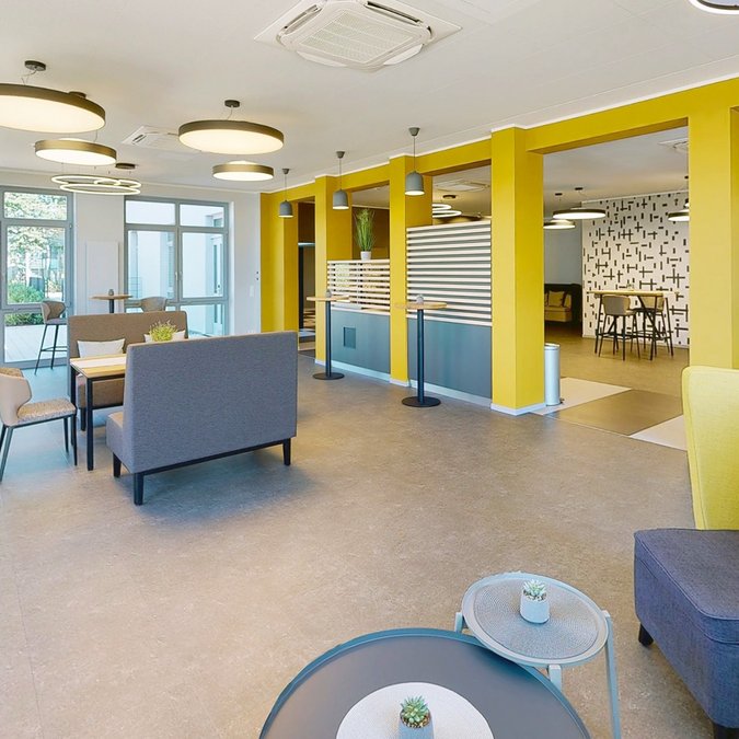 Median Hotel in Lehrte – wir geben Raum Moderner Aufenthaltsraum mit gelben Säulen und Sitzbereichen