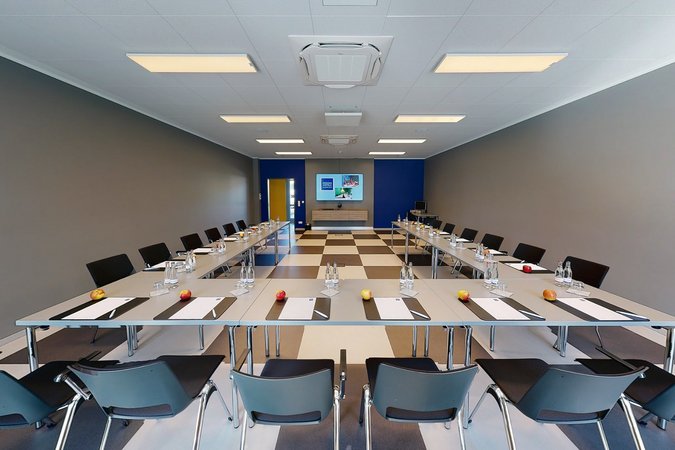 Median Hotel Hannover Lehrte Conference room with tables, chairs, water bottles, apples, and notepads