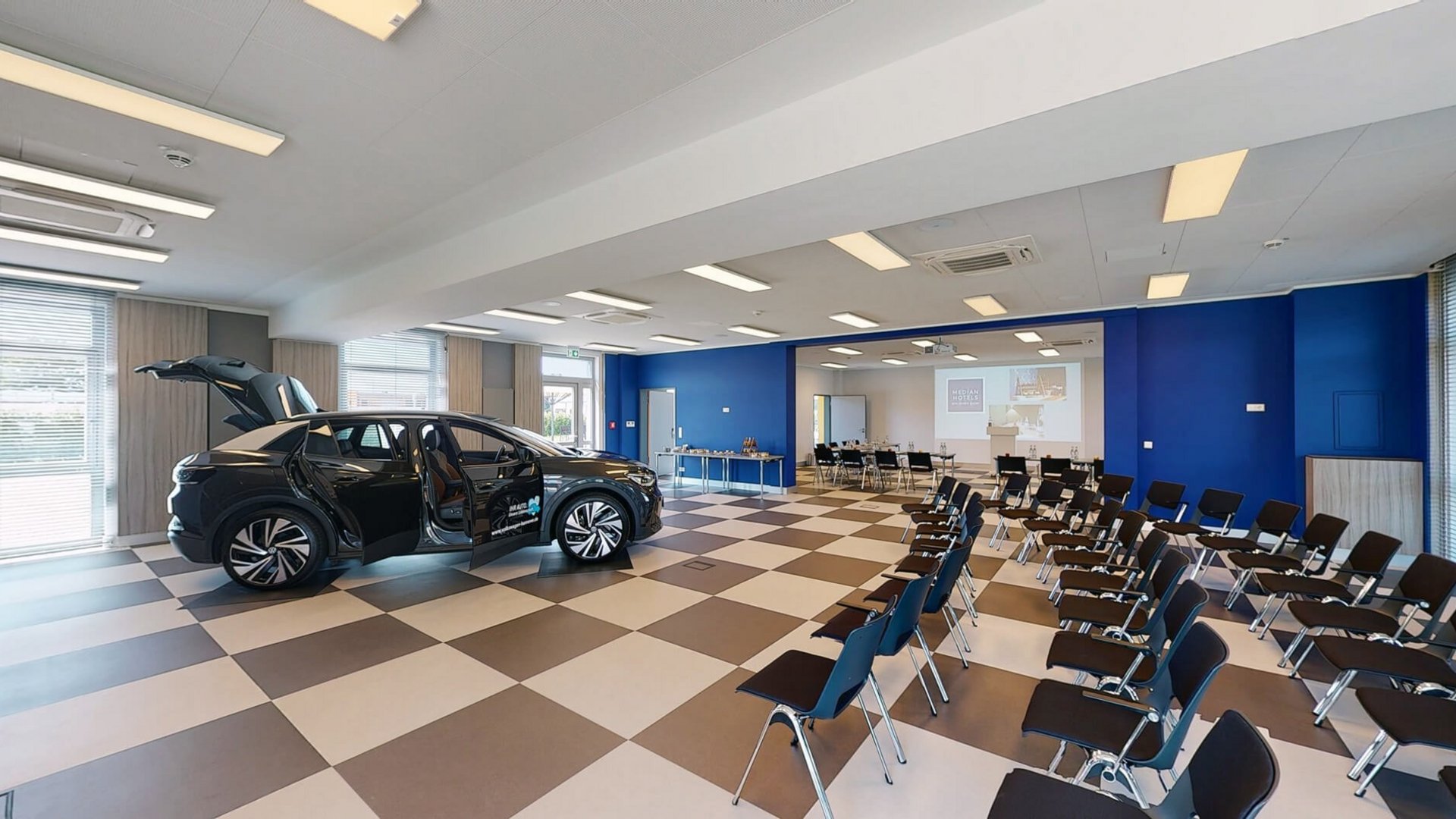 Median Hotel Hannover Lehrte Conference room with electric car and rows of chairs facing projection screen