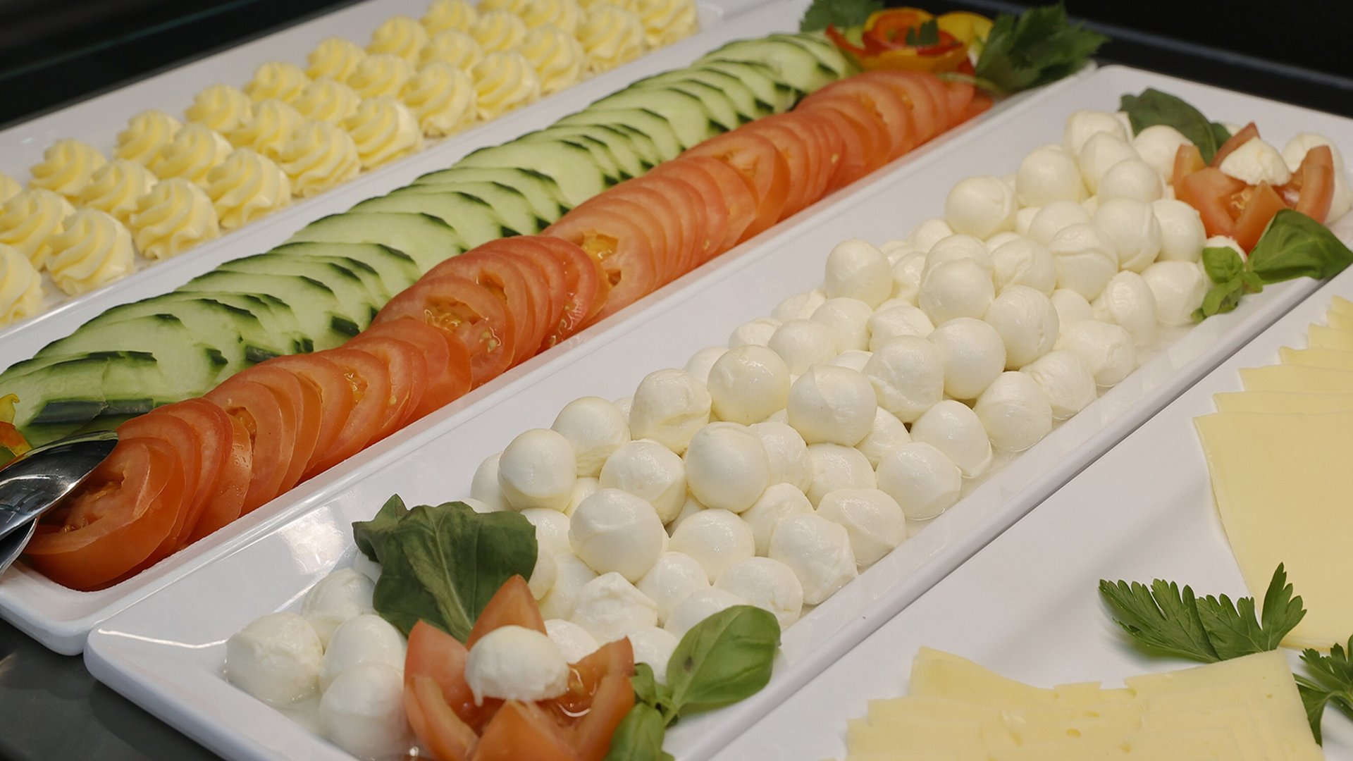 Room with breakfast in Hanover? Median Hotel! Platters with mozzarella, tomatoes, cucumbers, butter, and cheese on a buffet