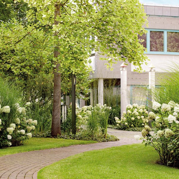 Median Hotel Hannover Lehrte Neat garden path with white flowers and green grass in front of a house