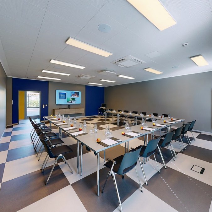 Median Hotel Hannover Lehrte Modern conference room with U-shaped tables, chairs, flat screen, and water bottles